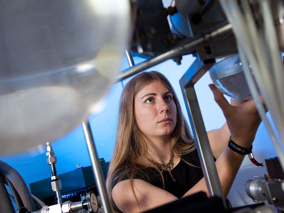 A person looks at a filled glass container in their hand.