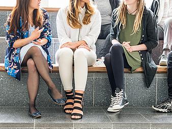 Studierende sitzen gemeinsam auf einer Bank.