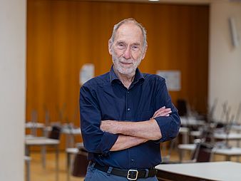 20211129_Frieder Nake_ Campusgeschichte Frieder Nake steht in einem holzgetäfelten Raum und schaut in die Kamera