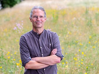 Professor Marko Rohlfs Ein Mann steht mitten in einer blühenden Wiese