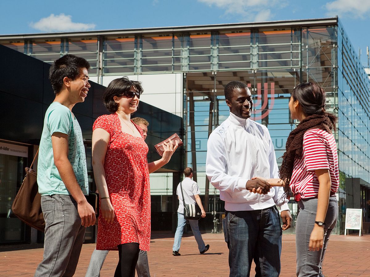 Vier Studierende im Gespräch auf dem Universitäts-Boulevard.