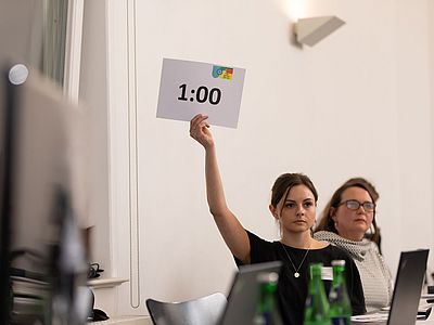 Laura Körlle hält 1 Minute Schild hoch