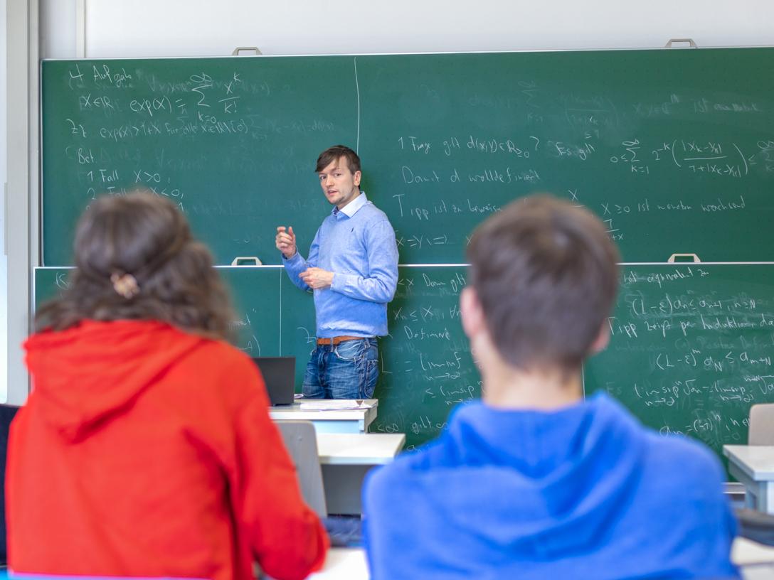 Junger Mann erklärt Formel an der Tafel