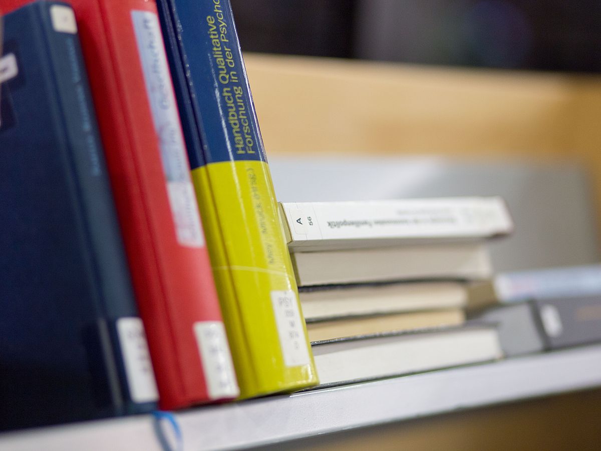 Bücher liegen im Regal.
