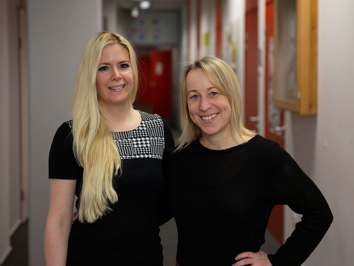 Zwei blonde Frauen mit schwarzer Kleidung lächeln