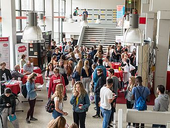Young people at information stands in a large building.