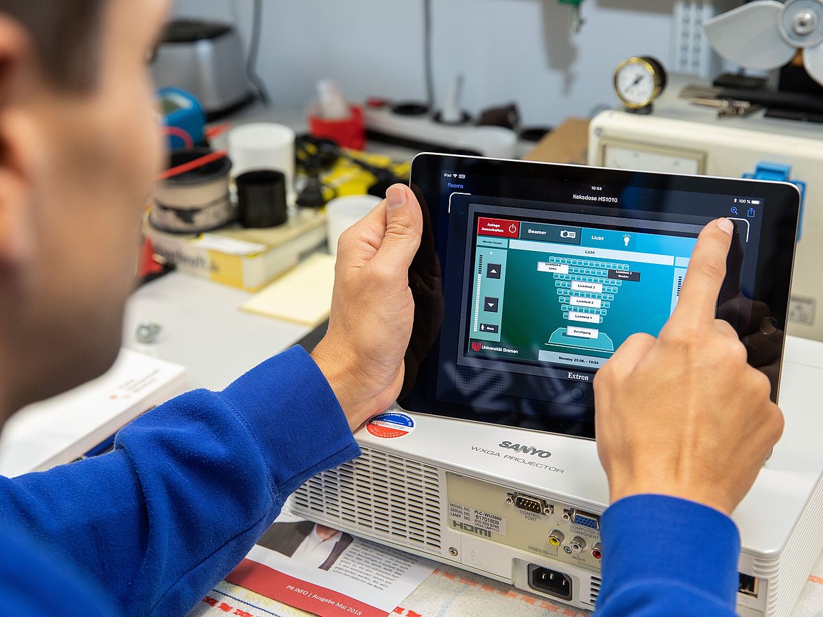 One person operates a tablet.