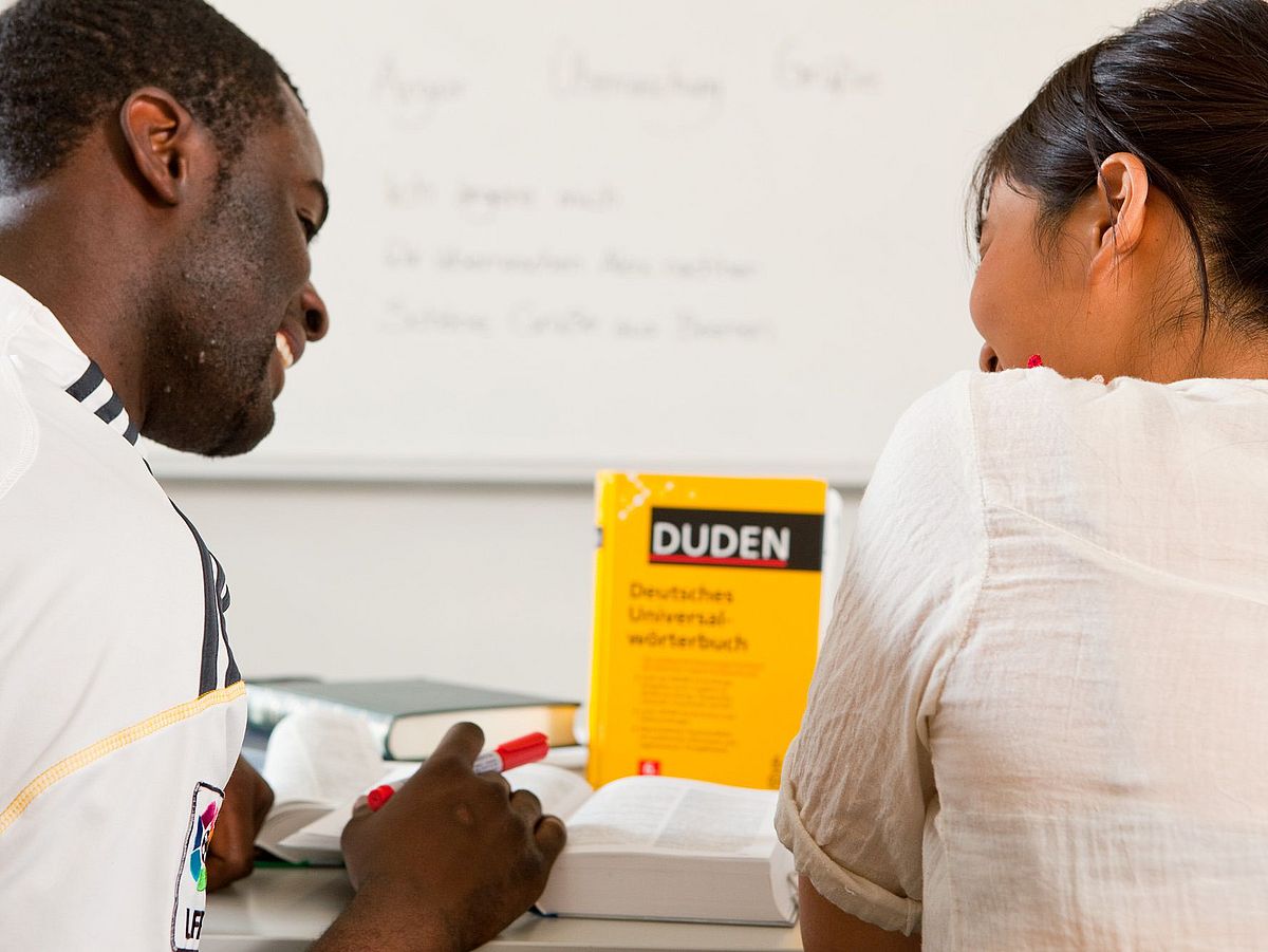 Two students work with a dictionary.