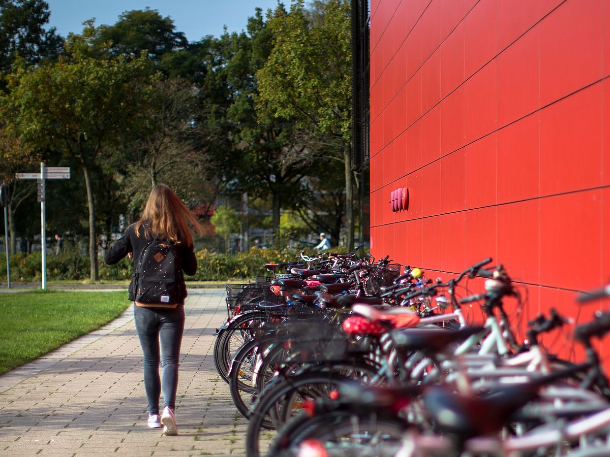 Eine Frau geht am Fahrradständer entlang.