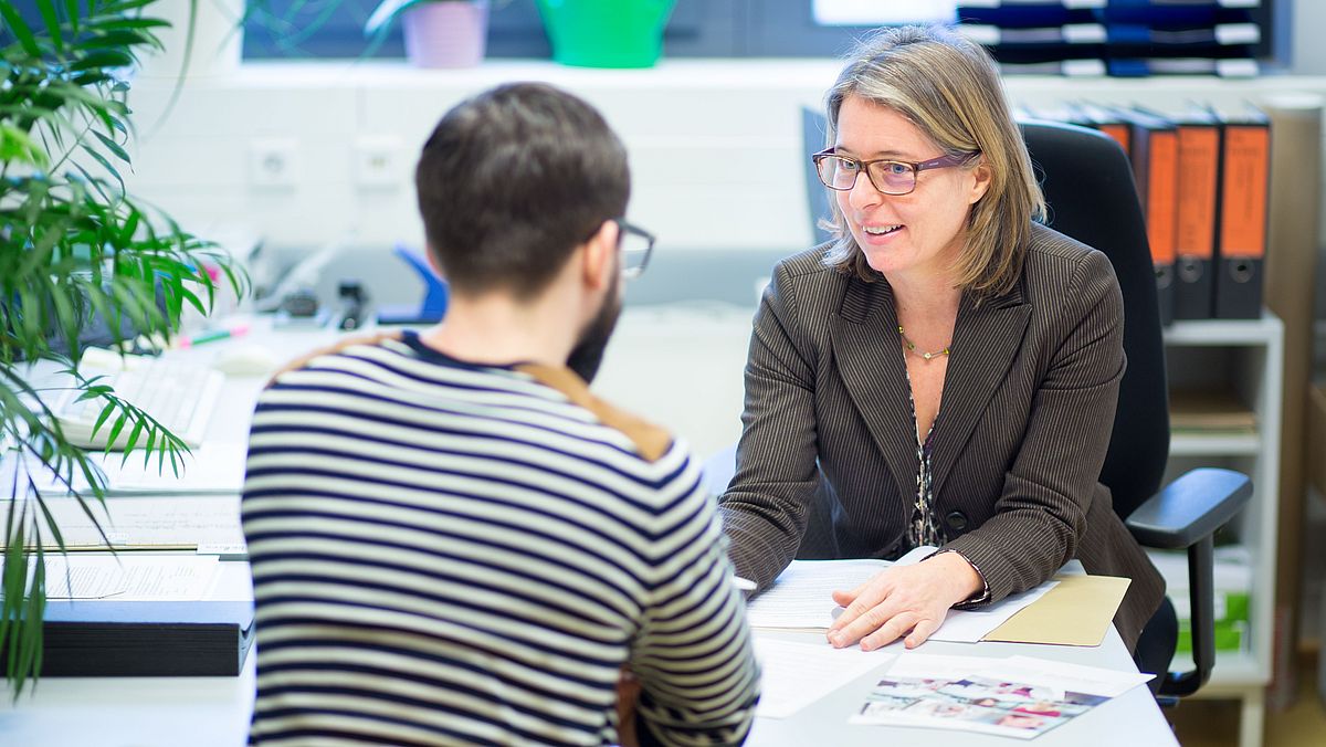 Two people in conversation at an office table.