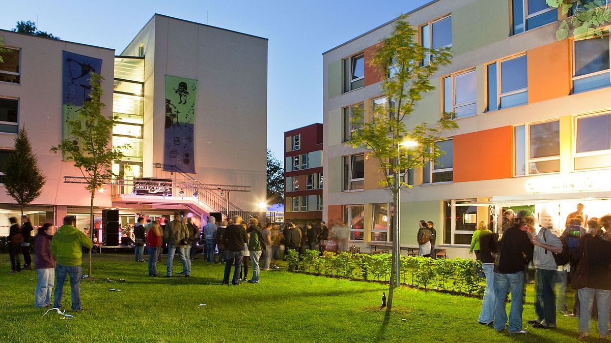 Crowd in front of a hall of residence at an evening event.