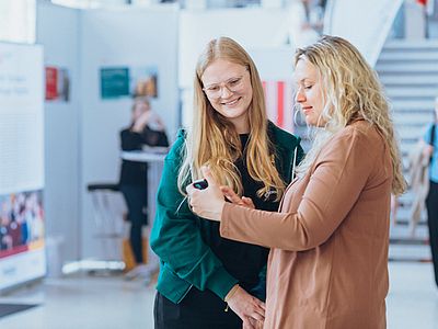 Eine Frau zeigt einer anderen Frau etwas auf dem Handy