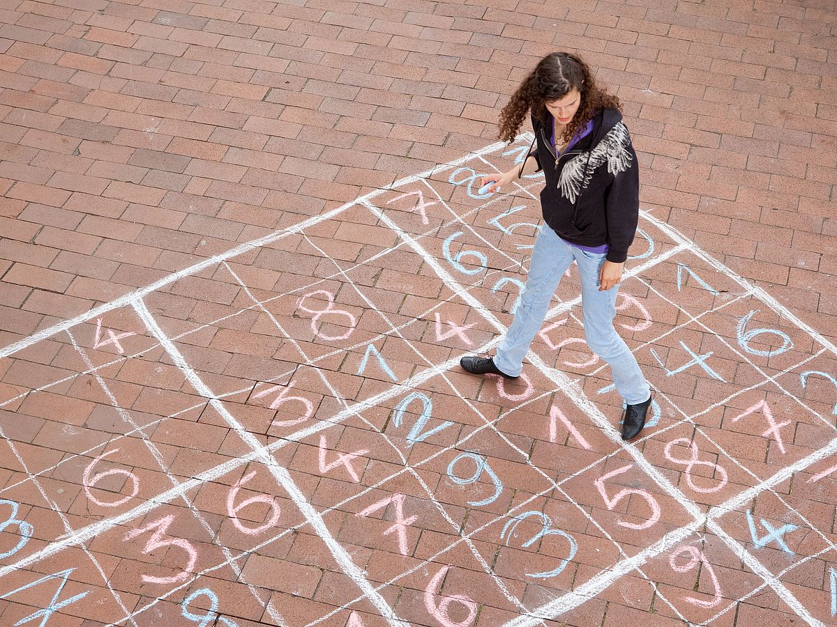 A person walks on a chalk drawn Sudoku game.