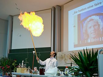 Mann im Kittel macht Experiment mit Flamme